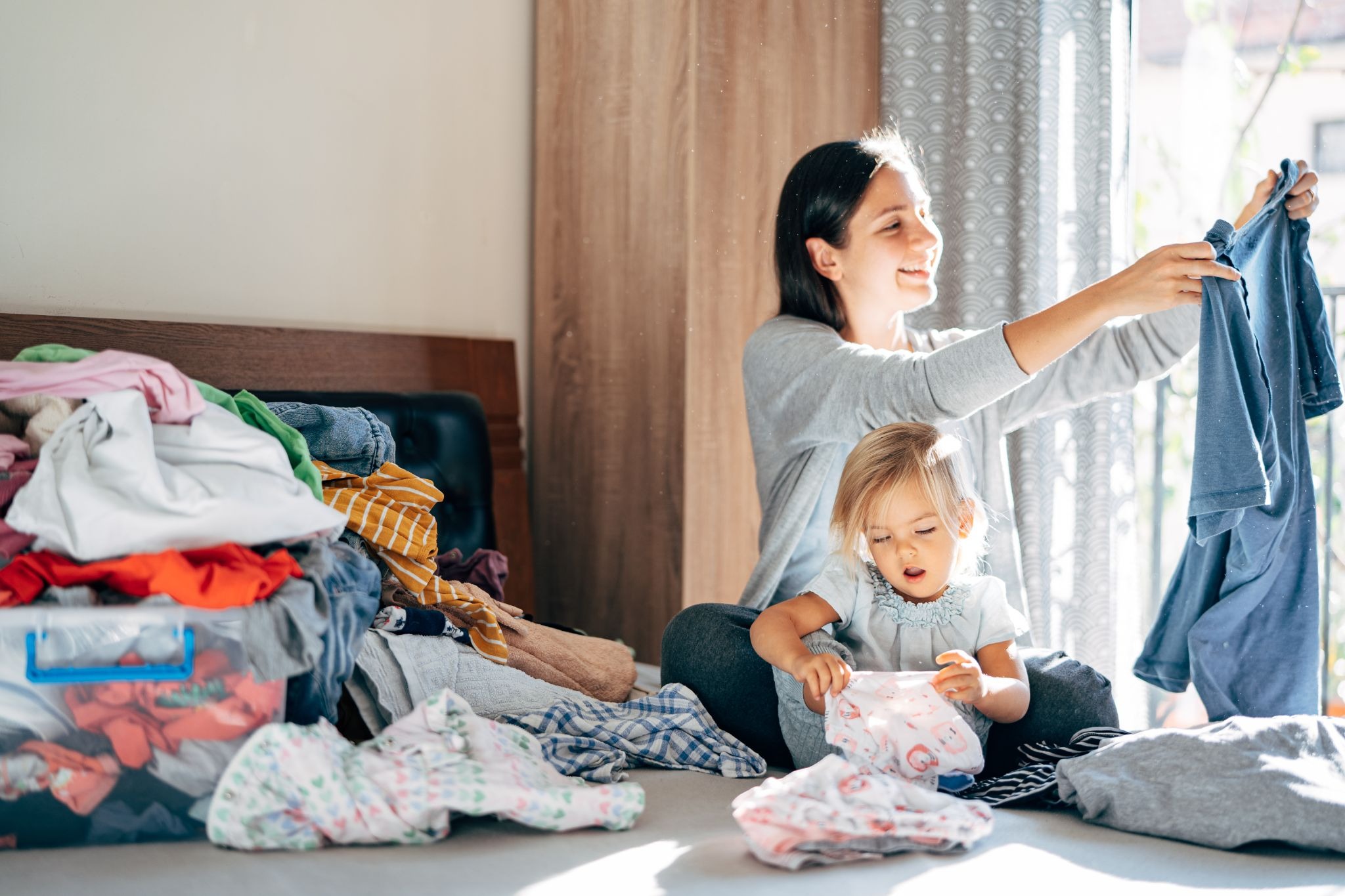 Mother and young child folding laundry together at home